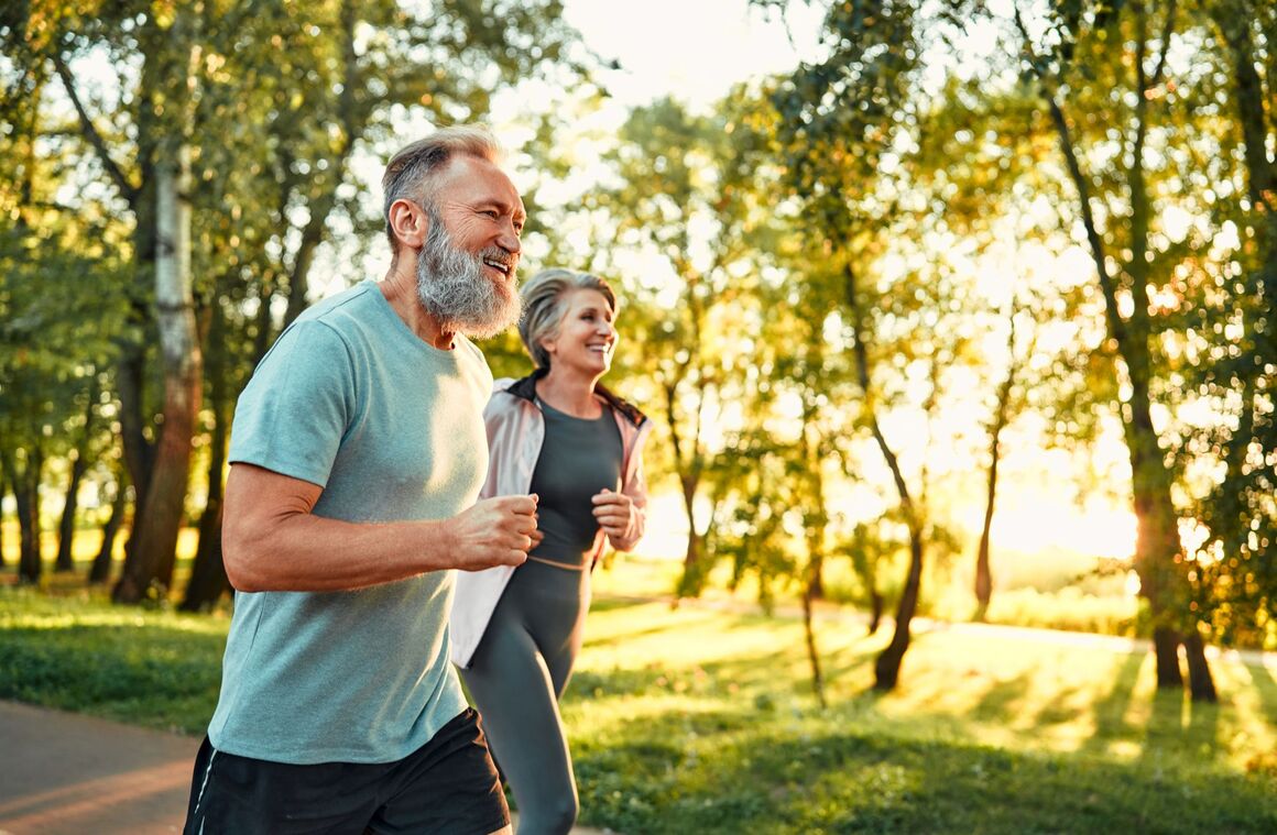 Älteres Paar joggt im Park bei Sonnenuntergang – Bewegung und Vitalität im Alter